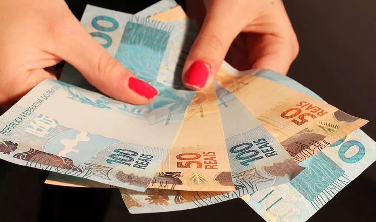 mulher segurando notas de dinheiro para representar redistribuição de renda