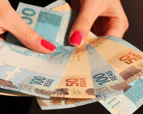 mulher segurando notas de dinheiro para representar redistribuição de renda